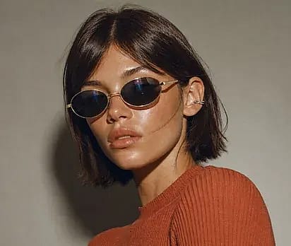 Portrait in oval sunglasses against warm grey