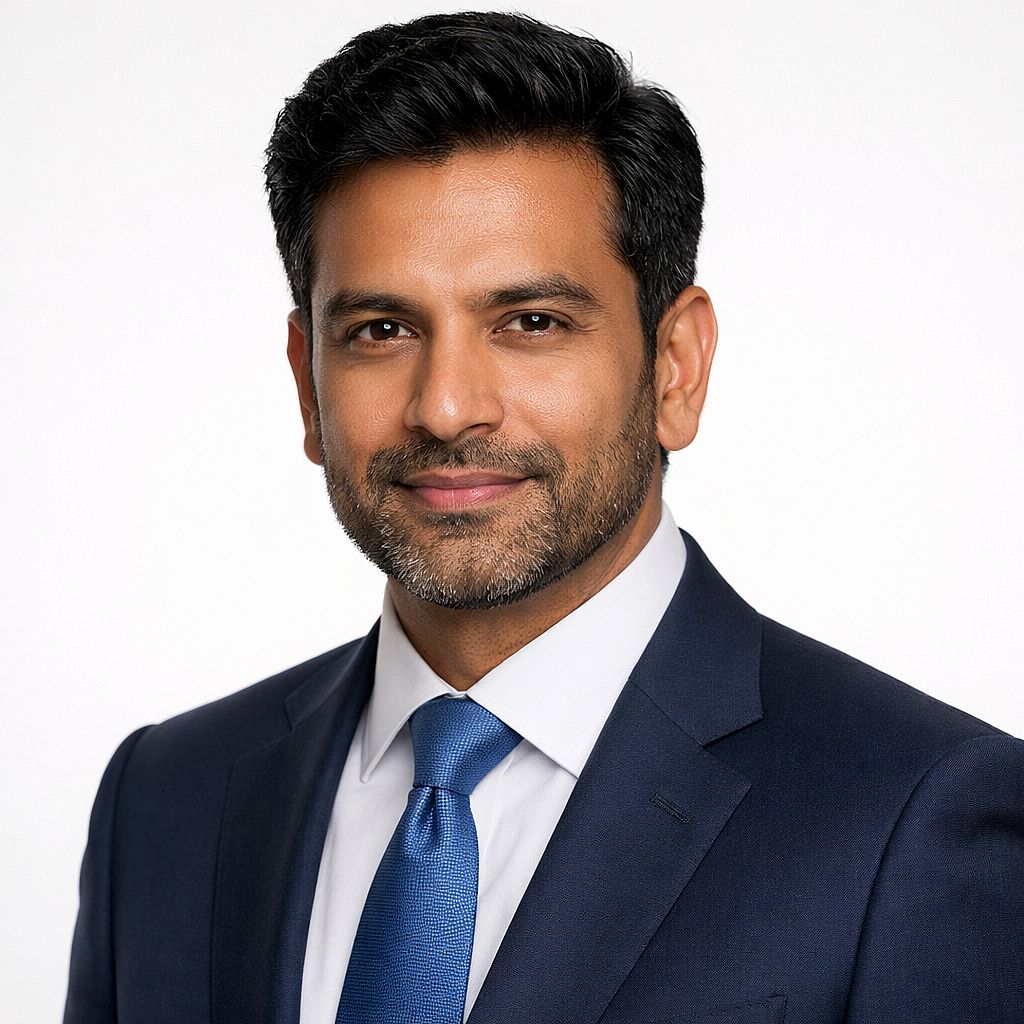 Corporate Headshot — Professional corporate headshot of a South Asian man in a navy suit, clean white studio ba