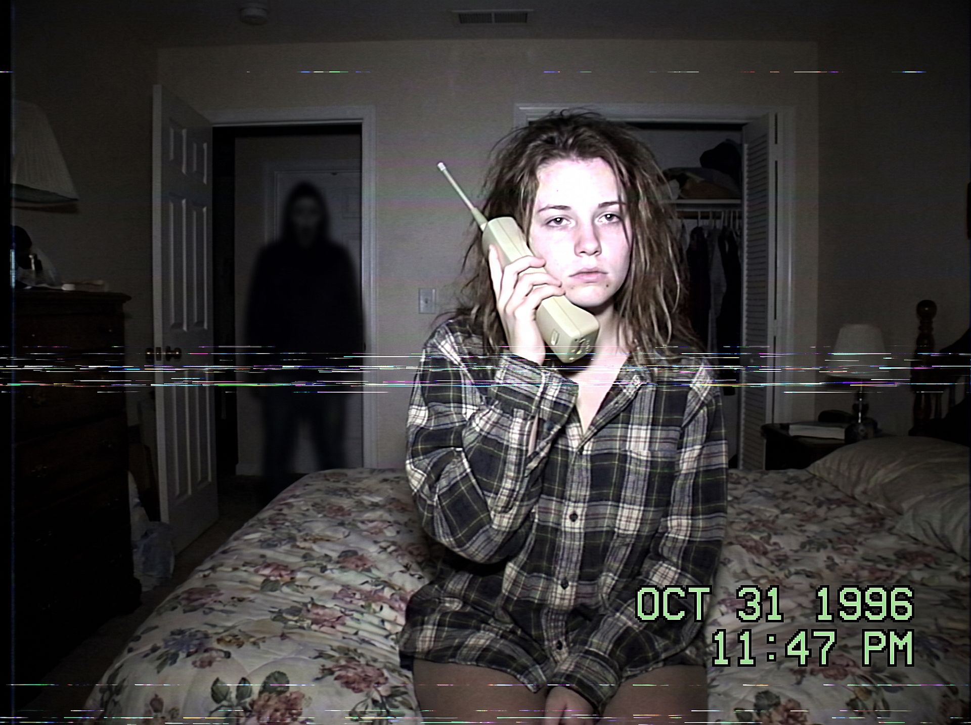 a photo restyled into a 90s VHS horror camcorder still with a shadowy figure in the doorway