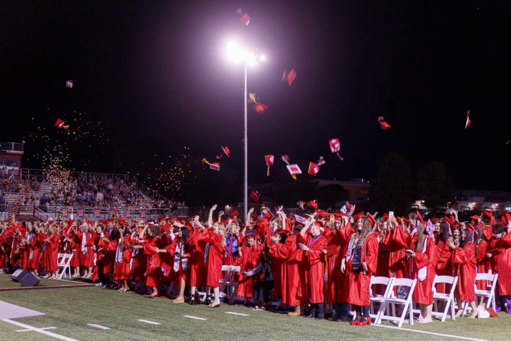 Prompt: students jump up and down as they celebrate graduation