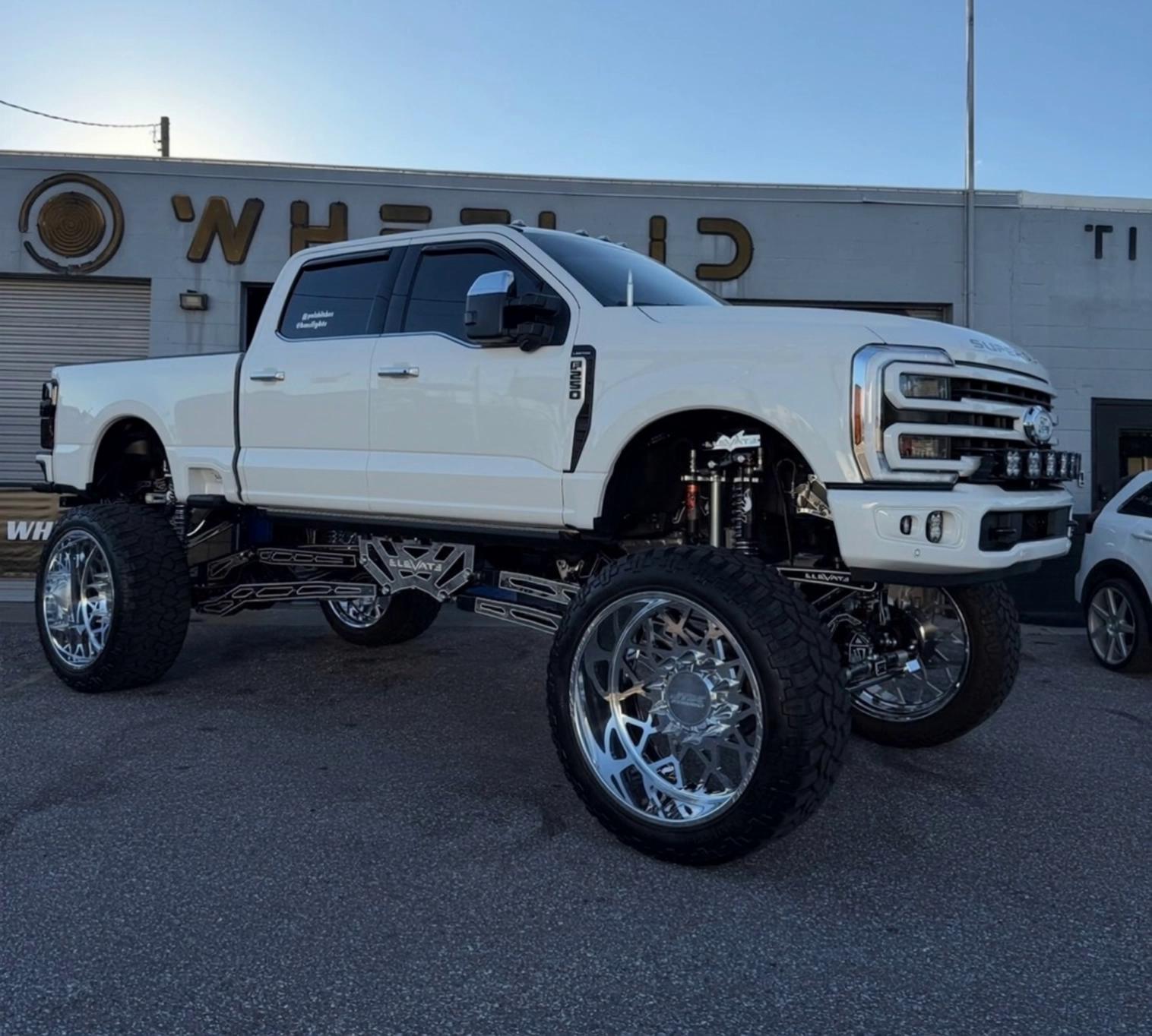 Prompt: Make this lifted customized truck look like a factory white f250 with regular wheels then transforms back to its lifted form again but even bigger. Illuminate the truck when it gets bigger and make the street underneath it crack. 