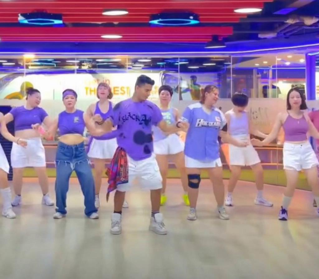 Prompt: Make everyone perform a fast, synchronized Digidi Digidi dance with energetic footwork, hip sways, shoulder moves and coordinated arm gestures. Keep faces, outfits and studio unchanged. Realistic full-body motion, fun expressions, smooth camera, viral dance style.