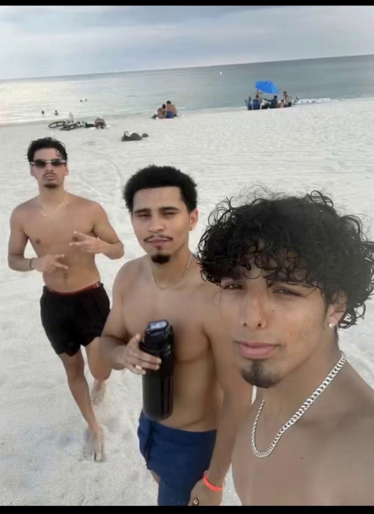 Prompt: Make the guy on the right holding the camera look back and lean in for a kiss on the guy in the middle