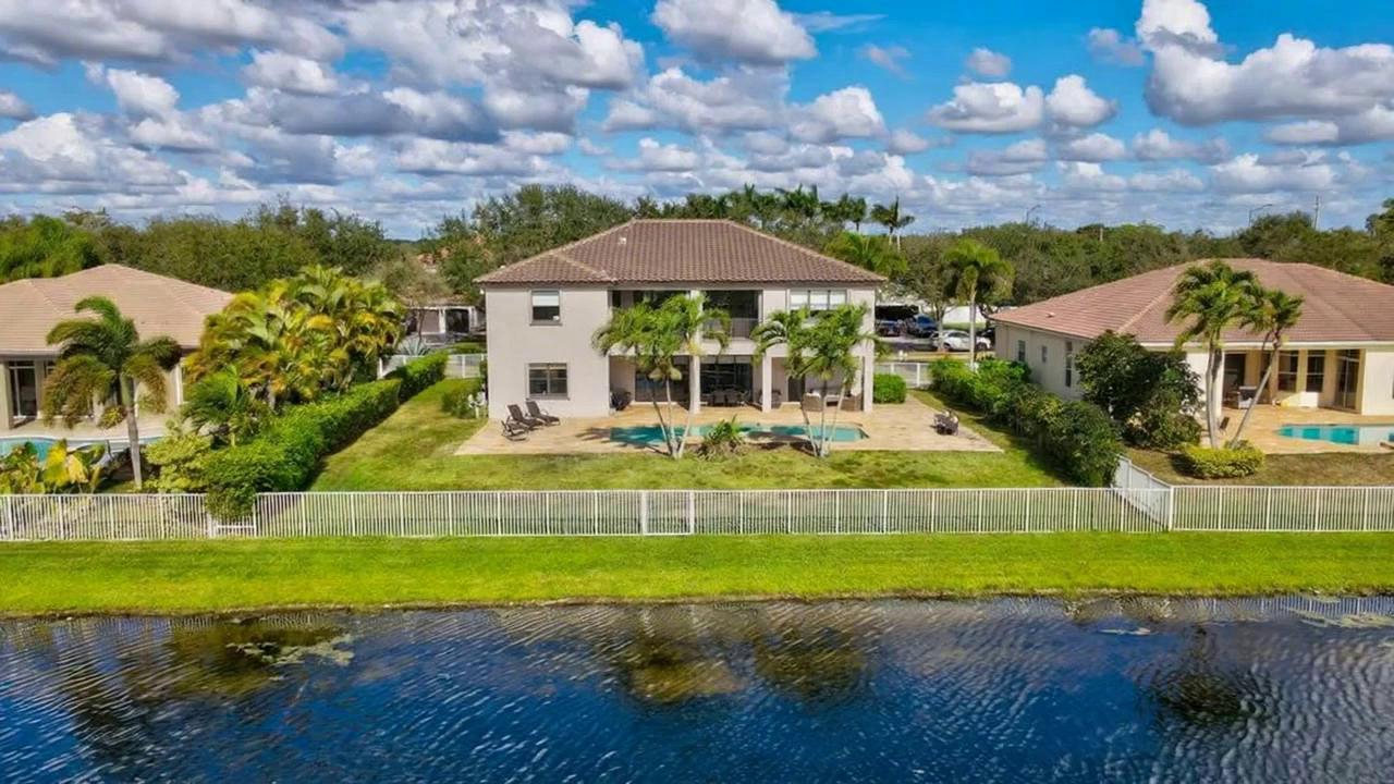 Prompt: The camera angle flys away from the home as the clouds whiz by overhead like a time lapse.  The view is as if a drone is flying away from the house.  As the video progresses, shadows shift across the landscape as the sunsets, the sky goes from blue to a pink sunset sky.