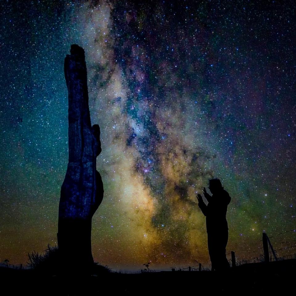 Prompt: starry sky moves slowly diagonally downwards, as electricity bolt fizzles from the standing stone which transforms into a goddess and back into a standing stone, bolt fizzez into the hands of the person who lights up momentarily before going dark again.