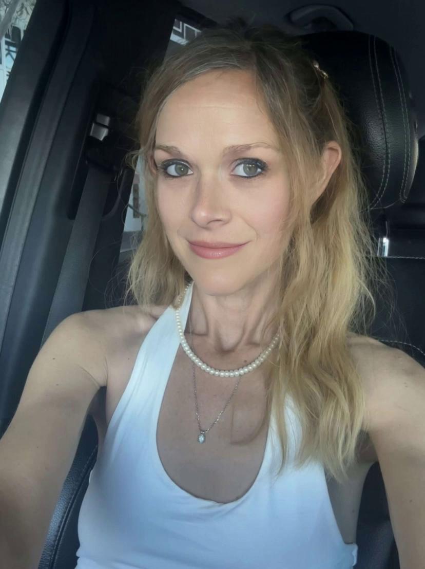 Prompt: The girl is smirking at her phone as she takes a selfie video. She opens her mouth and shows that she has mayonnaise inside her mouth. Right before it falls out she closes her mouth and smiles.