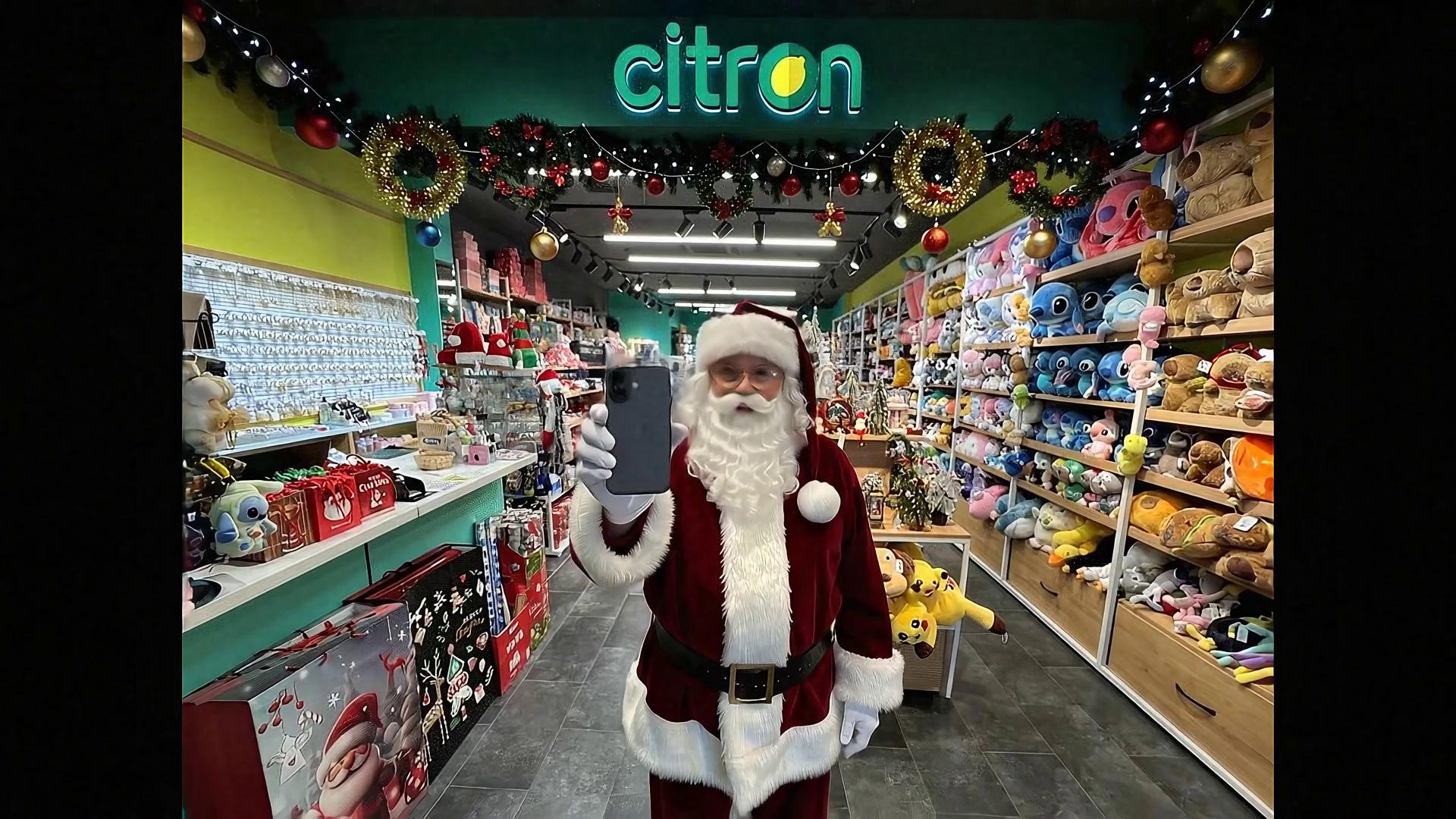 Prompt: 
VEO 3 PROMPT — PART 2 (Speech Fits Fully in Video)

Format: 16:9, UHD, optimized for large screens (75")
Audio: Romanian, soft, warm, pleasant tone
Brand: CITRON
Important: All Santa’s spoken lines must fully fit inside the video duration — natural pacing, no cut-offs.

🎥 Scene Start — After Part 1

Santa finishes the previous phrase:

„…și câștigă ultimul iPhone 17.”

He lifts the iPhone slightly closer to the camera.
The iPhone is exactly the same model as in the reference photo, showing:

dark gray matte back

dual cameras

flash above the top camera

clear visible Apple logo in the center

same angle, same camera orientation as in reference

Warm Christmas lights reflect softly on the phone. Snowflakes fall slowly in sharp detail.

🗣 Santa’s Lines — SHORTENED to Fit the Video

Santa smiles warmly and says in a soft, pleasant tone:

„Mai multe cumpărături, mai multe șanse de câștig!
În anul nou te faci cu un iPhone nou! Ho-ho-ho!”

Instruction to VEO:
Ensure the full spoken dialogue fits smoothly inside the video duration with natural pacing. No words should be cut or rushed. Maintain soft, warm intonation.

🎬 Final Scene

Snowflakes swirl gently.
Fade into the glowing CITRON logo in UHD quality.
Light snowfall continues over the logo.

🌟 Atmosphere

Cinematic, warm, premium holiday style.
Optimized for a 75-inch TV: sharp, full-screen, detailed.
Smooth camera motion, elegant lighting, calm magical mood.
