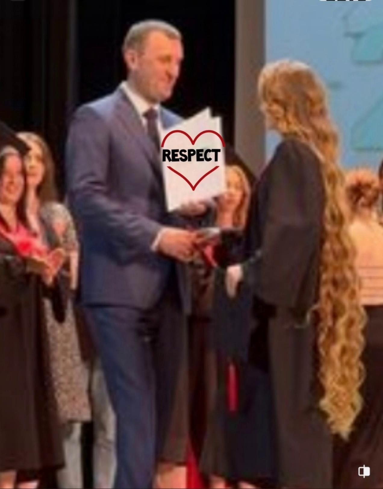 Prompt: Man hands the girl her certificate of respect as he shakes her hand