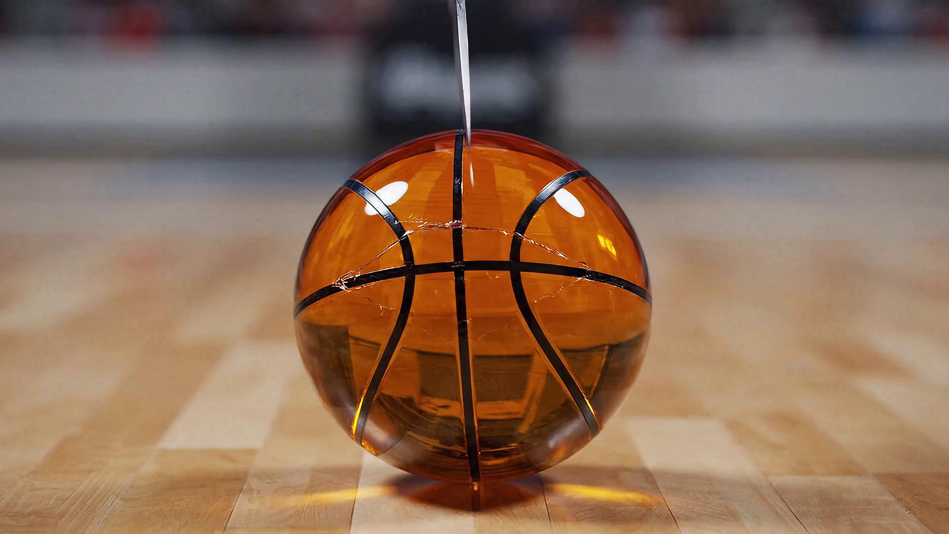 Prompt: Ultra slow-motion macro shot of a transparent orange glass basketball resting on a quiet indoor hardwood court (practice gym). Minimal background, soft blur, no crowd, no stadium ambience.

A human hand holds a stainless steel knife positioned directly ABOVE the exact center of the basketball, aligned perfectly vertical (top-down). The blade is perpendicular to the floor, pointing straight downward.

Absolute silence while the knife hovers — no tapping, no ambient sound.

Audio begins ONLY when the blade starts cutting downward through the glass. The knife moves in a straight vertical slicing motion, no horizontal movement, no sideways angle, cutting cleanly through the middle of the basketball.

The basketball splits into two equal halves that separate and fall in opposite directions.
Second sound event: realistic glass-on-wood impact and light shard scatter ONLY when the halves hit the hardwood floor. Audio fades back to silence.

No music. No speech. No pre-contact sound.

Macro lens, shallow depth of field, cinematic lighting, hyper-realistic glass physics, smooth ultra slow motion, visually and sonically satisfying ASMR.
