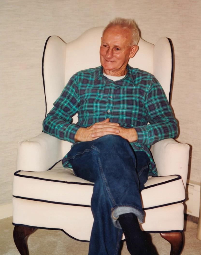 Prompt: Man sitting in a chair smiling, laughing and waving to the camera