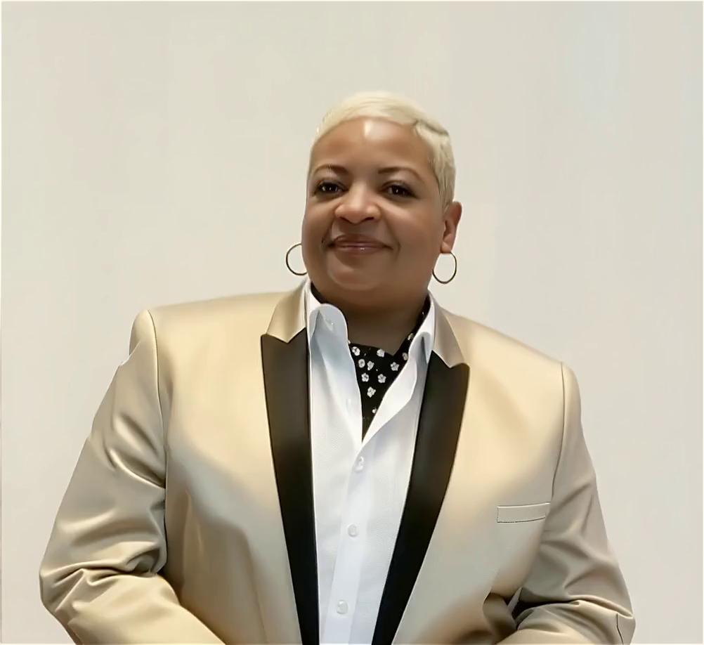 Prompt: A hyper-realistic cinematic 3D scene of Gwen GQ Clemons breaking out of a Facebook mobile timeline. She is stepping forward out of a smartphone screen feet first, in slow motion, as glass shards and digital pixels explode outward from the screen. One sneaker extends toward the camera in full 3D perspective, creating powerful depth.

Gwen looks exactly like the uploaded reference photo, with the same face, haircut, skin tone, and confident expression. She is wearing a red blazer, a red T-shirt that reads “My Pain Made Me Change,” fitted jeans, and red and black men’s Air Force 1 sneakers.

The smartphone displays a fully recreated Facebook interface:
• Facebook logo at the top
• Profile picture using Gwen’s photo
• Username: Gwen GQ Clemons
• Post title: “Leaving 2025”
• Reaction icons (Like, Love, Wow)
• Like, Comment, Share bar
• Bottom navigation icons (Home, Friends, Watch, Notifications, Menu)

Gwen starts inside the Facebook post image, then steps forward, breaking through the screen as if the phone is shattering into reality. Glass fragments and glowing digital pixels fly outward where she breaks through.

Lighting matches the original photo’s warm, studio-soft lighting, with cinematic highlights and shadows.

At the bottom of the screen, glowing bold text appears: “Stepping Into 2026”.

Style is cinematic, dramatic, ultra-realistic, movie-quality, high contrast, shallow depth of field, slow motion, epic energy, empowering and bold.