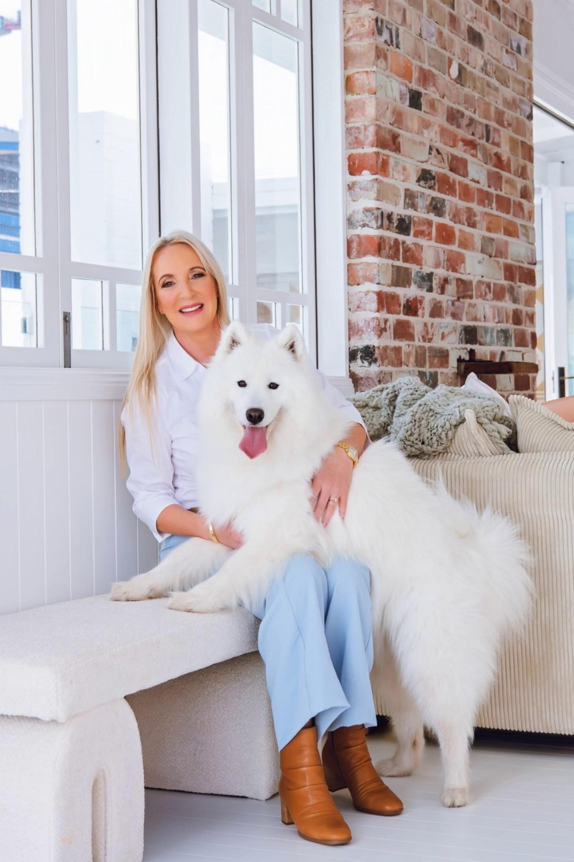 Prompt: stand up from sitting position and walk out towards the camera to a doorway with the fluffy white Samoyed dog following beside