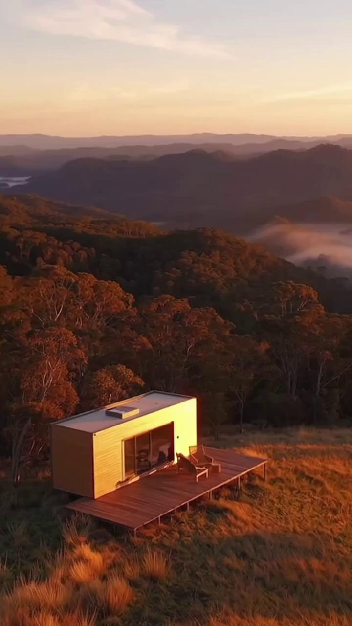 Prompt: A cinematic aerial video showcasing luxury off-grid tiny homes nestled in the rolling hills of regional Australia during golden hour. Smooth drone shots reveal minimalist architecture in tones of sand, clay, and bronze surrounded by eucalyptus forest and misty valleys. Soft sunlight glows through large windows. A couple enjoys coffee on the deck, another scene shows a designer interior with linen bedding, timber textures, and candlelight. The pacing is slow, meditative, and elegant — matching the tone of high-end wellness brands like Aesop or Alba Thermal Springs. Include ambient nature sounds and gentle piano music. Mood: calm, refined, soulful. Brand logo fade-in at end with tagline: “RUH Retreats — Refined Escapes for the Modern Soul.”