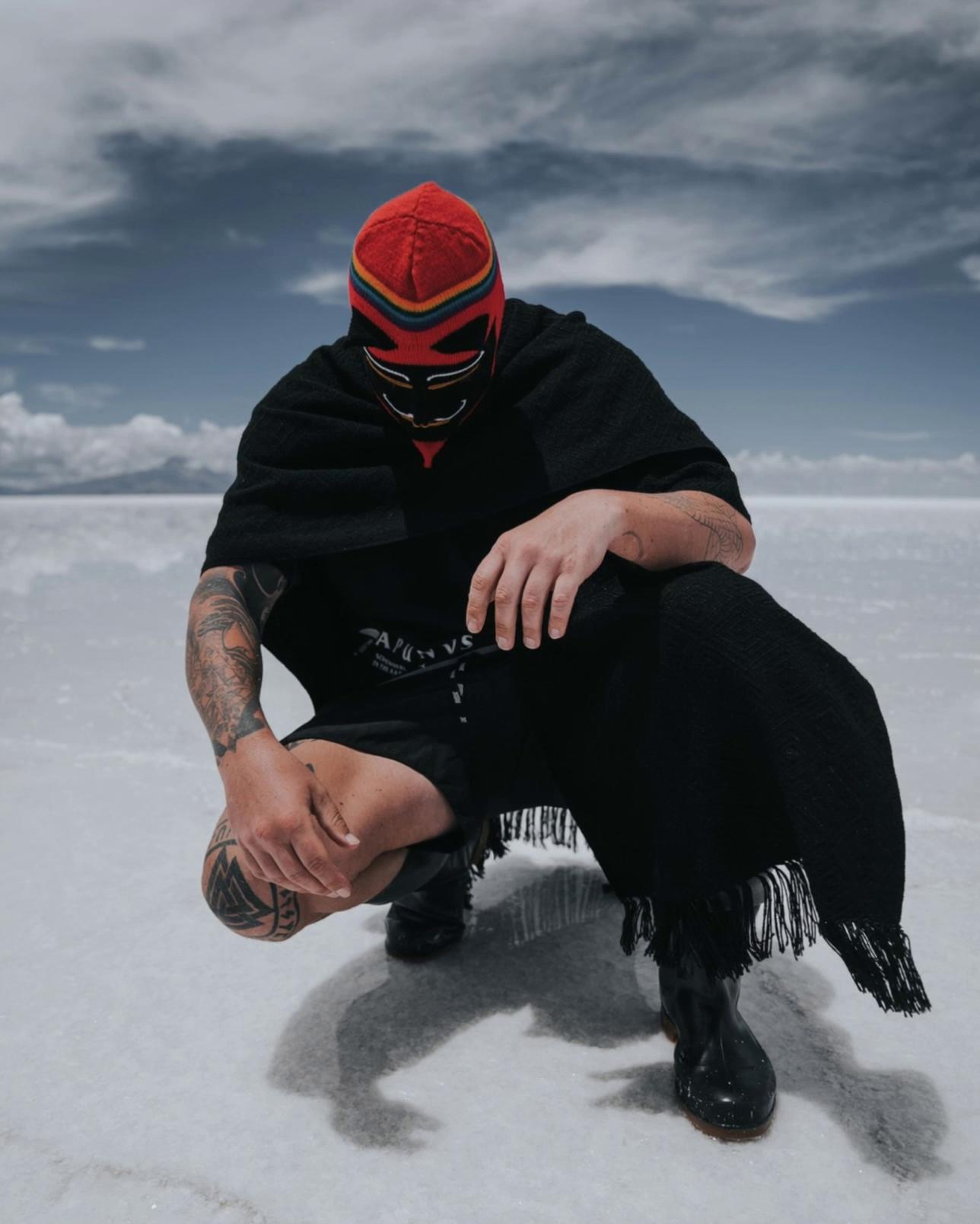 Prompt: A person slowly lifts their head and looks toward the camera. Their black poncho gently sways in the wind.