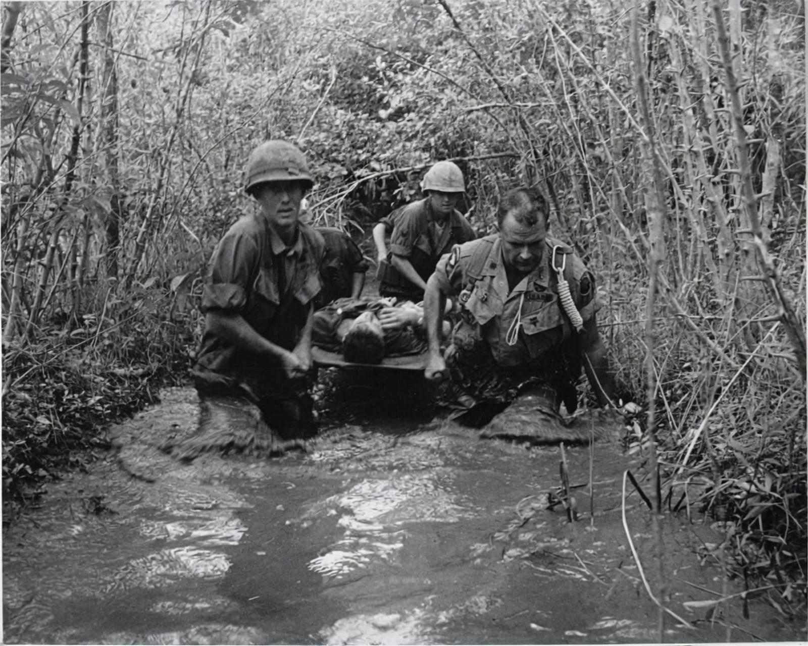 Prompt: Create a scene where they continue to walk towards the camera through the muck and mire of the swamp in the photo. 