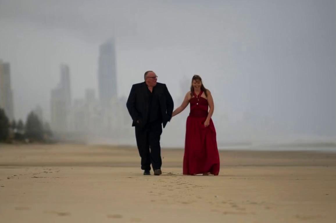 Prompt: create a walking video of couple coming towards camera and laughing and looking at one another and half way through clip jumping in the air and there are fireworks in the sky.
