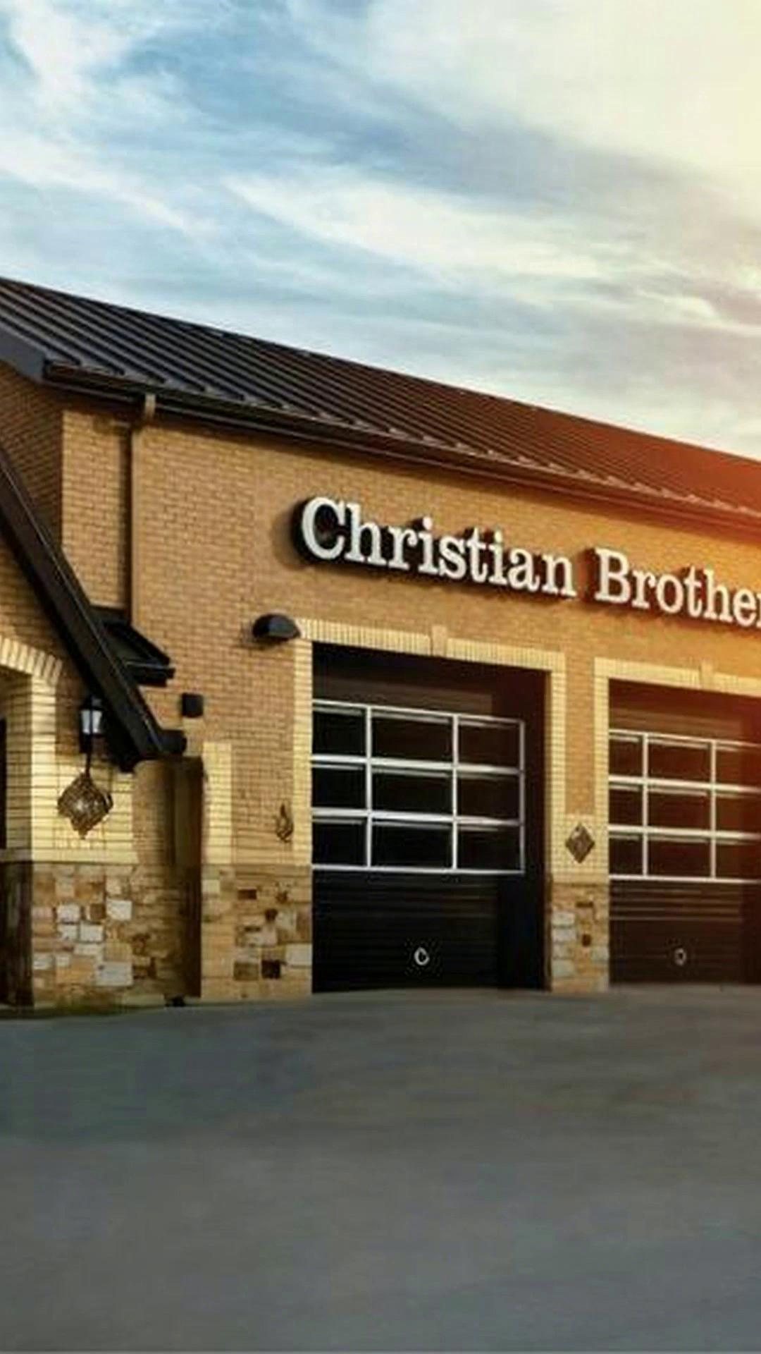 Prompt: Create a cinematic, realistic video from the provided image. The white Christian Brothers Automotive service vehicle smoothly drives from rightleft to right along the driveway in front of the building. The camera remains locked in a slight wide-angle perspective, maintaining the same framing as the original image. The vehicle slows naturally and comes to a stop in the exact position shown in the original image. After the vehicle fully stops, Lighting remains warm and consistent with golden-hour tones. Subtle motion in the sky and light reflections on the vehicle add realism. No camera shake.  no vehicle shake when it comes to a stop.
