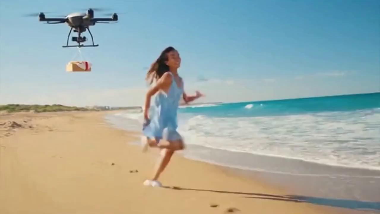 Prompt: American girl running down the beach in the middle of the day, then a drone flys down  delivers her a hamburger.