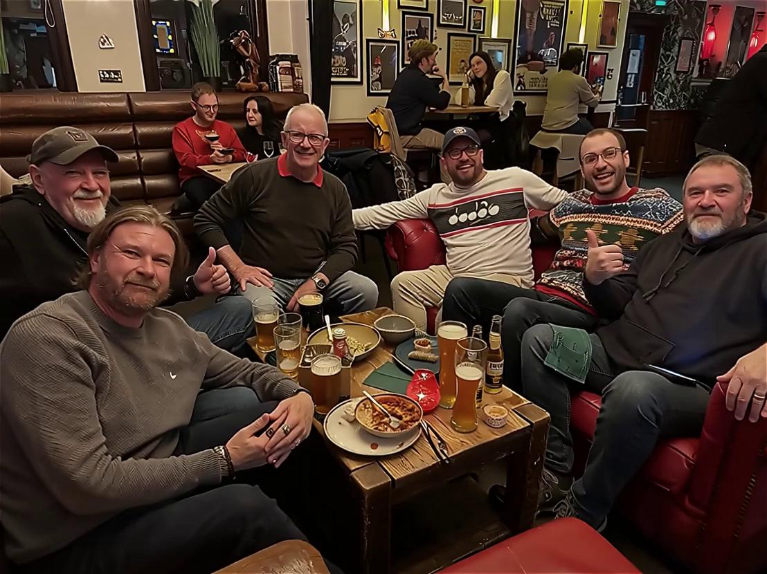 Prompt: all the men stand up,raise their glasses of champagne to say cheers ,looking at camera, all smiling