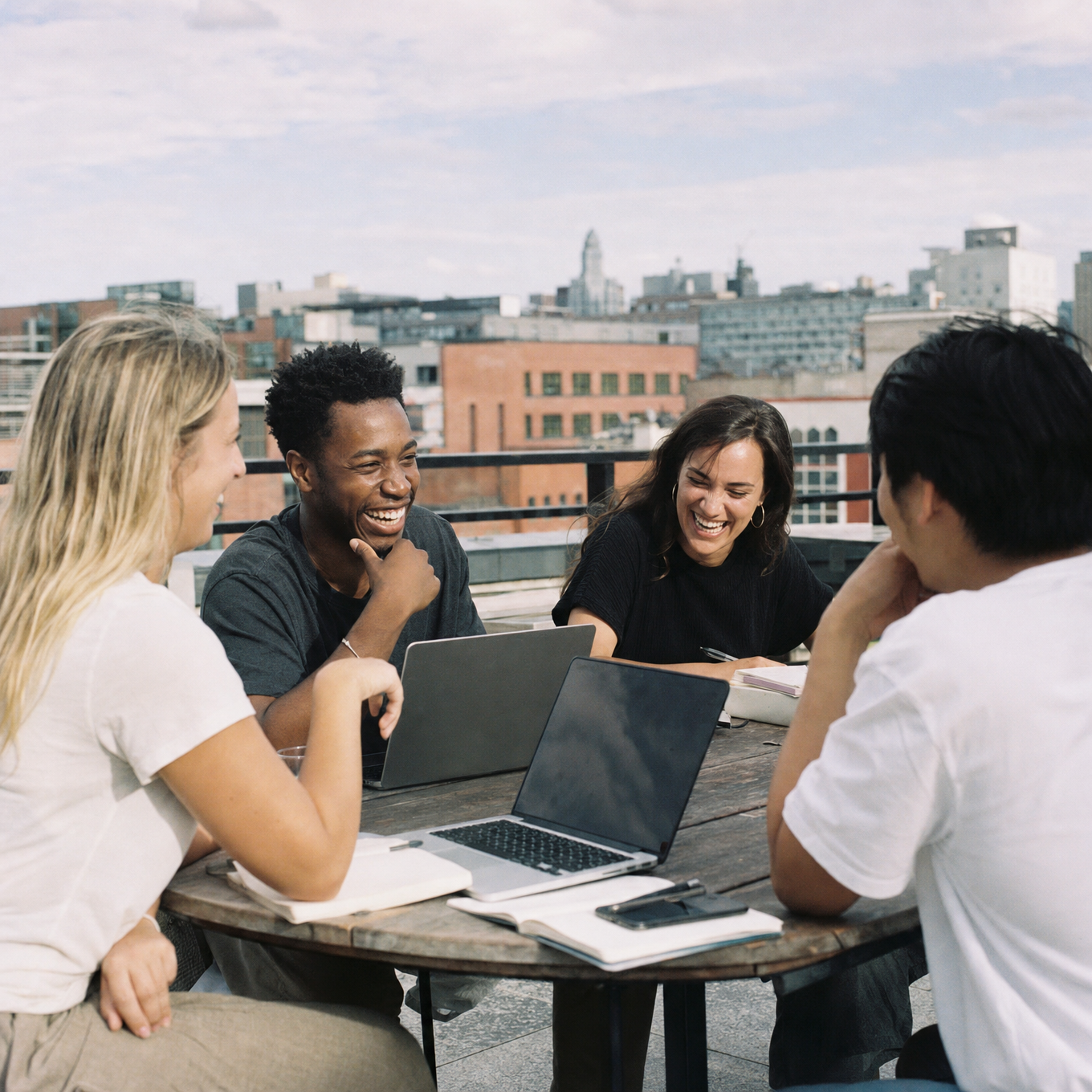 Small group of professionals genuinely collaborating at an outdoor rooftop table