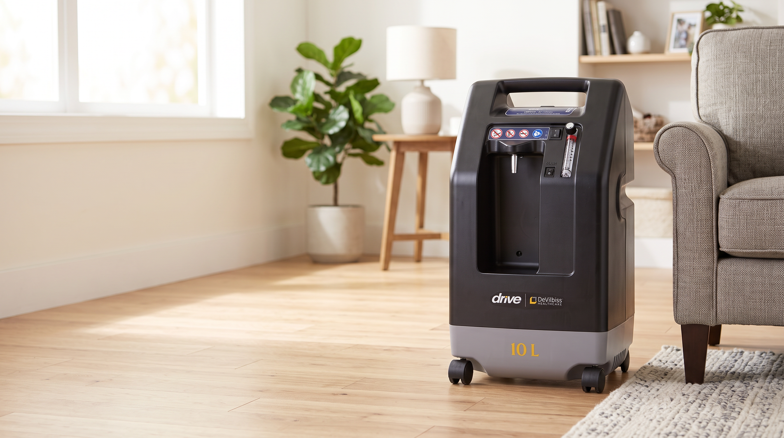Drive DeVilbiss 1025DS 10L home oxygen concentrator beside an armchair in a warm home living room