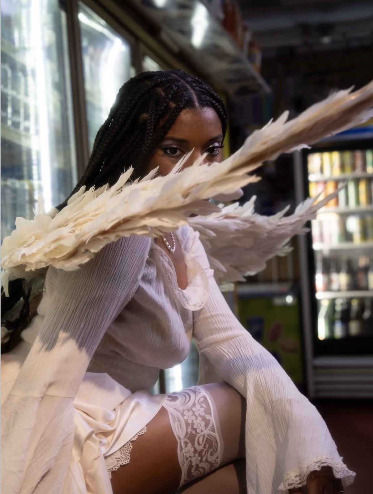 Dani Offline in white styling framed by sculptural feather-like forms