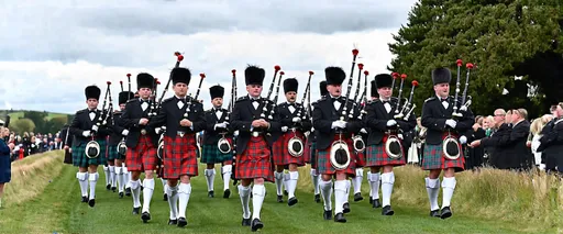 Prompt: An impressive sight as the Drum Majors lead the massed pipe bands, followed by the Atholl HIghlanders, through Braemar to the 2024 Braemar Gathering and Highland Games on Saturday 7th September 2024. The bands were playing Farewell to the Creeks on the march as they prepared for their noon display around the Highland Games field. 
The bands taking part were the Lonach Pipe Band, Huntly & District Pipe Band, Dunnottar Pipes and Drums, Ballater & District Pipe Band, Gordonstoun Pipe Band, Granite City Pipes & Drums, Kintore Pipe Band and Blairgowrie, Rattray & District Pipe Band.