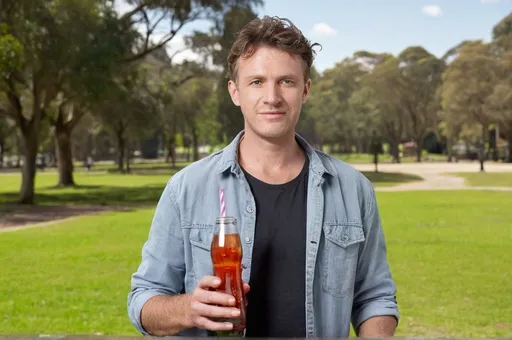 Prompt: a man australian holding a glass of flower in his hand and a bottle of soda in his other hand, with a park background, Andries Stock, dada, product photo, a stock photo