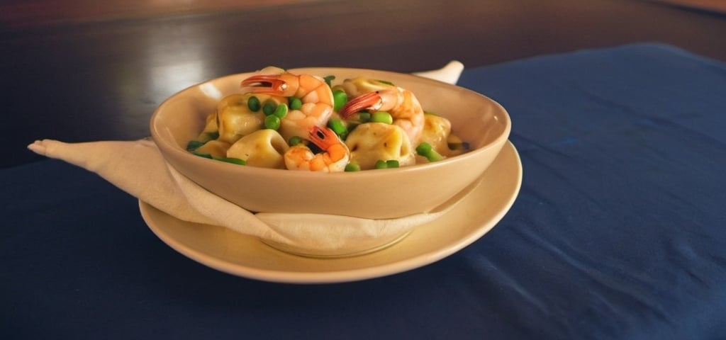 Prompt: A bowl of (Baked gnocchi, shrimp, tortellini, spicy cream sauce & green onions)  on napkin on a plate on a table, regionalism,  food photography.