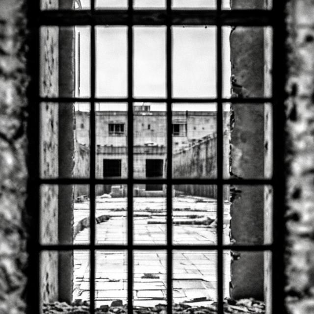 Prompt: a large prison cell wall, a city destroyed after the war, a view of a small destroyed window of a prison with prison bars. real photo. hd. GENERAL PLAN. vertical photo. see the felt completely