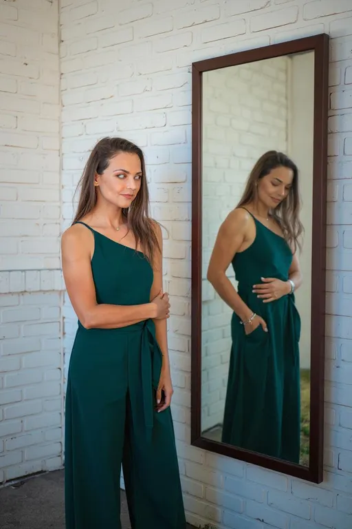 Prompt: create an image of a very thin and frail looking young girl similar to the reference images, standing with a mirror angled against the wall, the mirror is full sized , her expression in the mirror looks dull, tired, fatigued and miserable . 