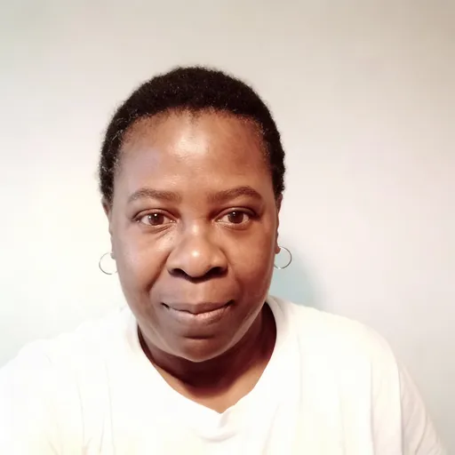 Prompt: Maintain exact facial structure, proportions, and identity from the reference image. Do not alter face shape, eye spacing, nose, lips, or age.
Ultra-realistic professional headshot based on the reference image. Dark-skinned woman in her early 30 with short natural afro hair, soft rounded facial features, warm brown eyes, smooth natural skin texture. Calm, confident, approachable expression. Minimal makeup, natural eyebrows. Wearing a simple white top. Clean light background, soft studio lighting, realistic camera depth. Bright, well-rested eyes. High-resolution portrait. No glasses, no heavy retouching.