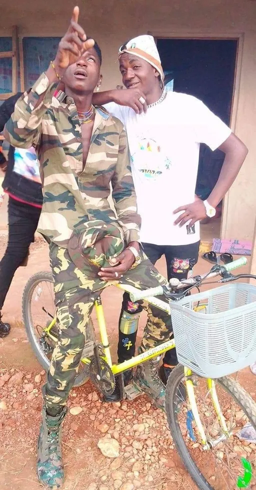 Prompt: ALi Boubacar Army soldier Military two men standing next to a bike 