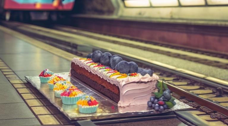 Prompt: The train that brings a cake to Milan leaves from the pastry shop on platform 9 coming from Rome;
