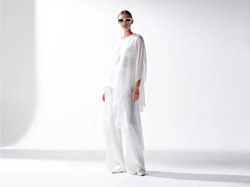 Prompt: a woman stands in a high fashion studio environment entirely defined by soft white tones, the space minimal yet deeply textured through subtle variations of light and shadow, her outfit composed of flowing white fabrics with delicate structure, layers of silk and matte textiles creating contrast without breaking the monochrome palette, her posture relaxed but intentional, one shoulder slightly forward, her body aligned in a way that feels both natural and composed, the lighting soft yet directional, sculpting her face with gentle gradients, eliminating harsh shadows while maintaining depth, the background seamless, blending into the floor with no visible edges, creating a sense of infinite space, the sunglasses become the central contrast element, a clean white frame with slightly tinted lenses, reflecting minimal highlights from the environment, the reflections controlled and soft, never distracting, her expression calm, neutral, almost introspective, as if existing in a space beyond distraction, every detail in the image carefully reduced to essentials, no visual noise, only form, light, and presence, the composition balanced with negative space, allowing the subject to breathe within the frame, the overall feeling one of clarity, refinement, and quiet confidence, high fashion editorial photography style, soft diffused lighting, high key exposure, minimal composition, clean aesthetic, ultra sharp subject with soft background falloff