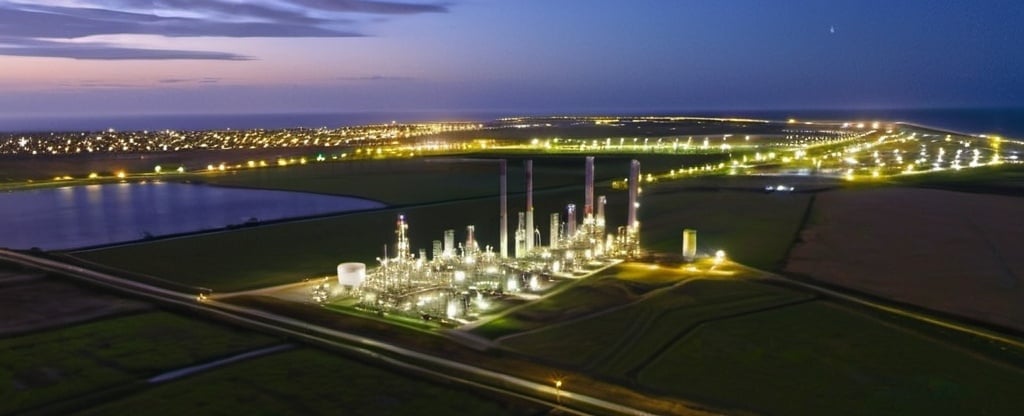 Prompt: arial photo of renewable chemical plant in a field near the coast at night. 
