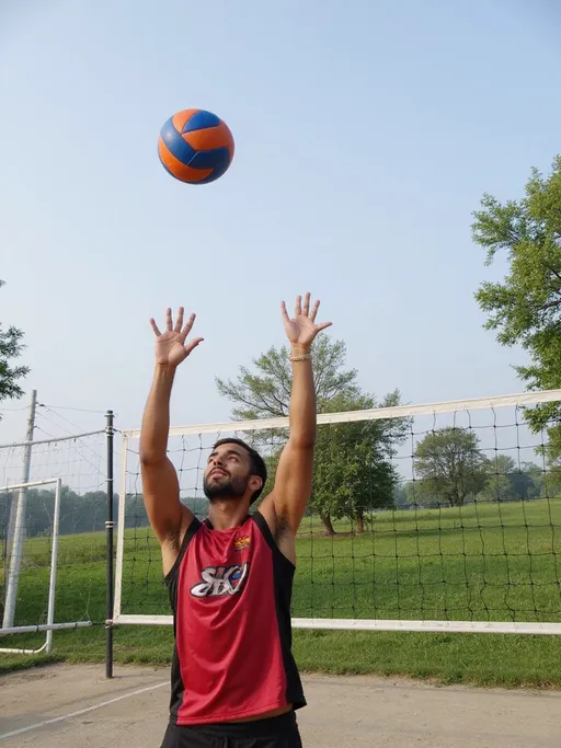 Prompt: Caught in a moment of athletic concentration, a young man clad in a vibrant red and black jersey extends his arms towards a volleyball suspended in the clear blue sky. His upward gaze reflects determination as he prepares to make a play, while the net behind him indicates an outdoor volleyball court set against a backdrop of lush greenery. The scene is bathed in soft daylight, suggesting a serene afternoon, with gentle shadows cast by trees that frame the field. The contrast of the bright blue and orange ball against the clear sky adds an energizing pop of color, embodying the thrill of sport and the hope of a great play. The atmosphere is filled with an adventurous spirit, capturing both the intensity of the game and the beauty of the surroundings.