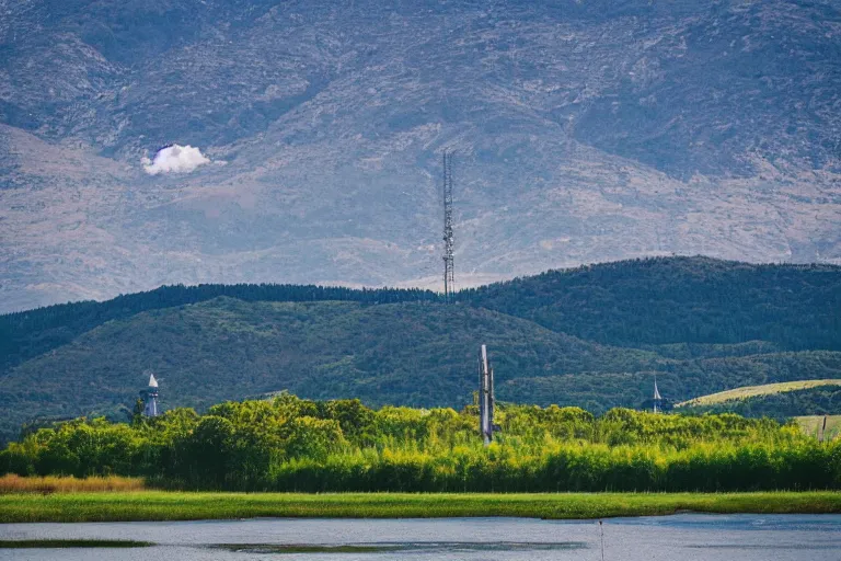 Image similar to a hill with a radio tower next to a pond, hills in background. telephoto lens photography.