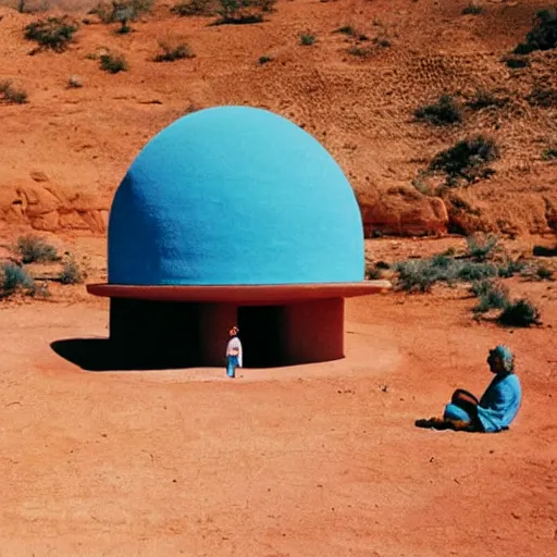 Image similar to a man in brightly colored clothing standing outside a Non-Euclidean orb-like clay house sitting in the desert, vintage photo, beautiful cinematography, blue sky, film grain, James Turrell