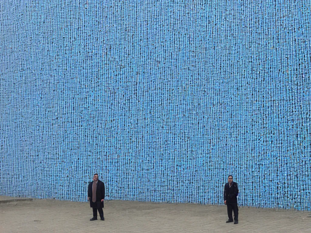 Image similar to a perfect portrait photograph of a human being reduced to an ordered set of pixels, sorted by the blue channel value, each pixel is a 1 meter plastic cube glued to the outside of a horrific government building in azerbaijan.