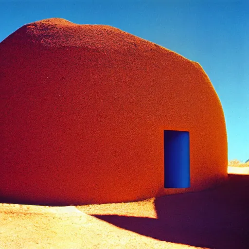 Image similar to a man in brightly colored clothing standing outside a Non-Euclidean orb-like clay house sitting in the desert, vintage photo, beautiful cinematography, blue sky, film grain, James Turrell