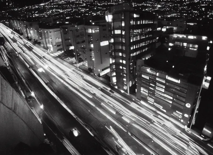 Image similar to looking up at a sprawling building complex seen from a dark parking lot in los angeles at night. 1 9 9 0 photo by james cameron