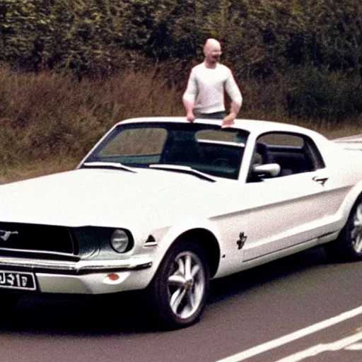 Image similar to coloured photograph of a muscled young white bald guy with broad shoulders, black shirt and a large chest driving a racing red mustang down a british road, high detail