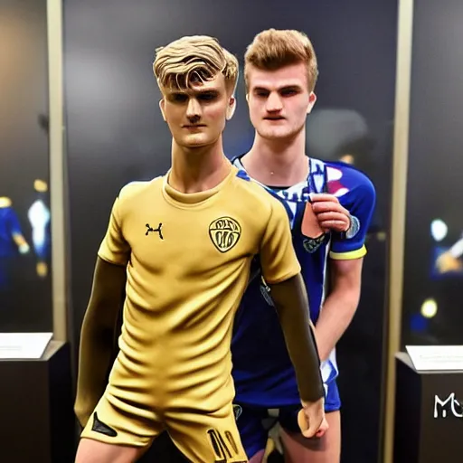 Prompt: a realistic detailed photo of a guy who is an attractive humanoid who is half robot and half humanoid, who is a male android, soccer players martin ødegaard & timo werner, shiny skin, posing like a statue, blank stare, in a museum, on display, showing off his muscles, gold soccer shorts, no jersey, side to side, statue