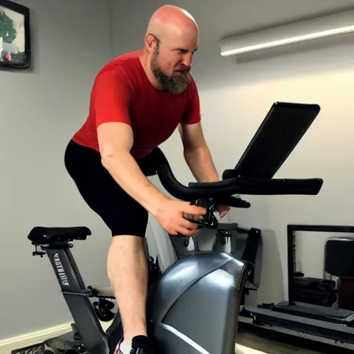 Image similar to ethan van sciver with a bald head and grey trimmed beard working out vigorously on his peloton exercise bike