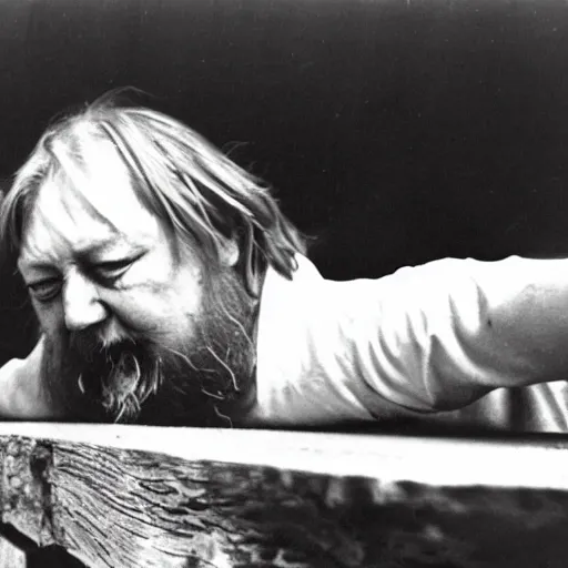 Image similar to robert wyatt gnawing on a long plank of wood, black and white photograph