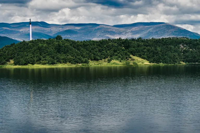 Image similar to a hill with a radio tower next to a lake, hills in background. telephoto lens photography.