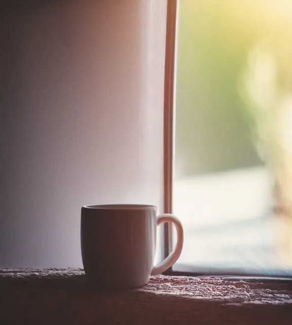 Image similar to a 4 k photorealistic photo close up of a mug on a sunny windowsill.