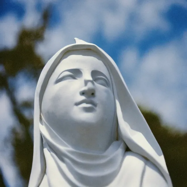Image similar to white statue of mother mary pictured slightly from below, clear sky with blue clouds in background, polaroid
