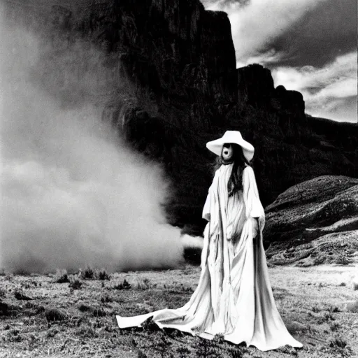 Image similar to 1 9 7 0's artistic western movie, a woman in a giant billowy wide flowing waving dress made out of white smoke, standing inside a dark western rocky scenic landscape, volumetric lighting